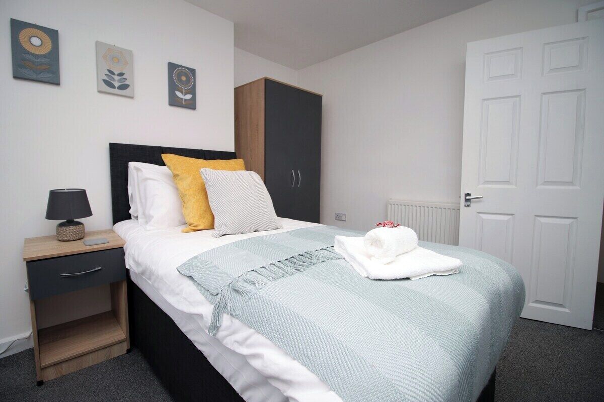 A neatly arranged bedroom with a bed, bedside table, and a wardrobe.