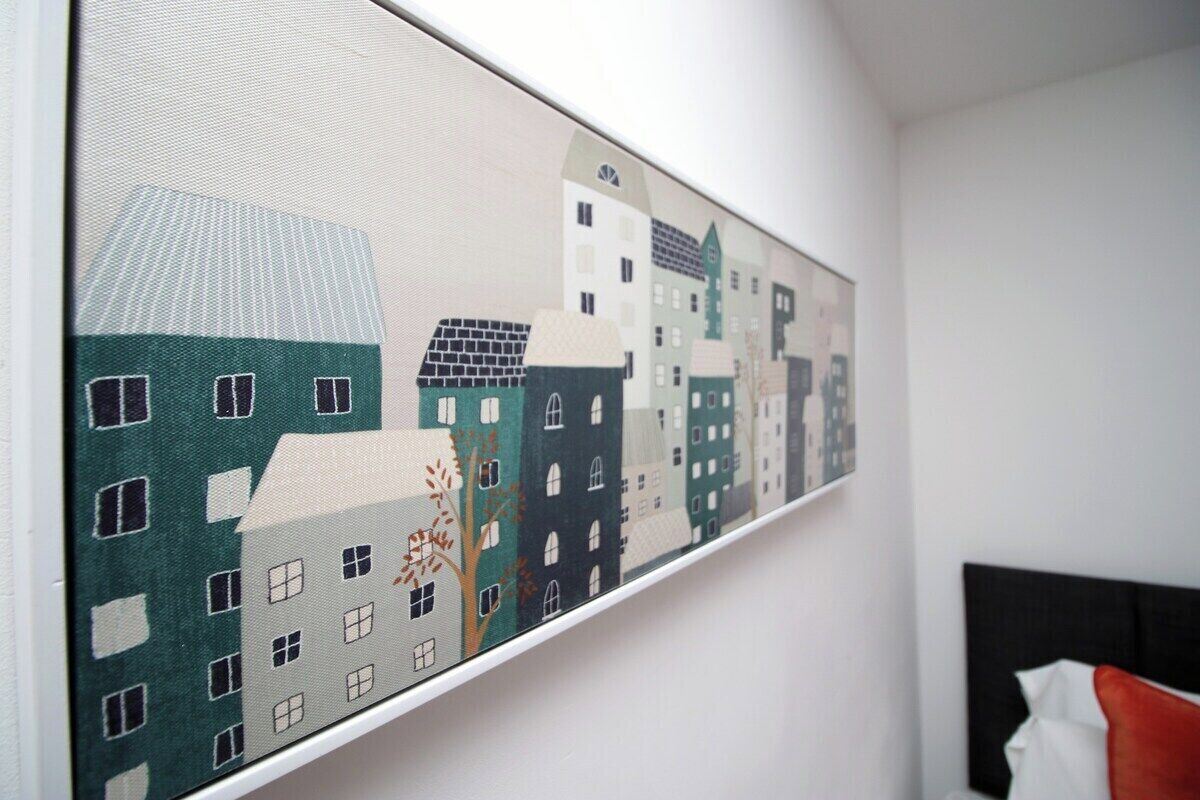 A long, narrow painting of stylized buildings on a wall.