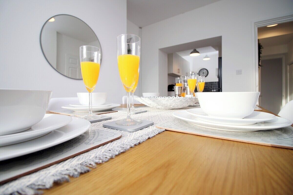 A dining table set with white plates, bowls, and glasses of orange juice.