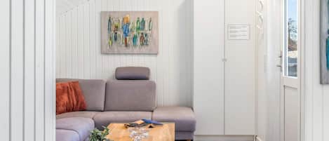 A modern living room with a grey sofa, a wooden coffee table, and a painting on the wall.