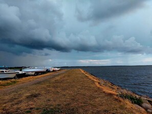 A grassy path beside a body of water with several boats docked on the left. - 4 Person Holiday Home in Hemmet (Hemmet)