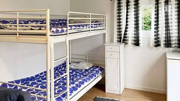 Quarto com beliche, escrivaninha e janela com cortinas.
