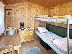 Habitación con literas, un escritorio, una cafetera y una cómoda pequeña.