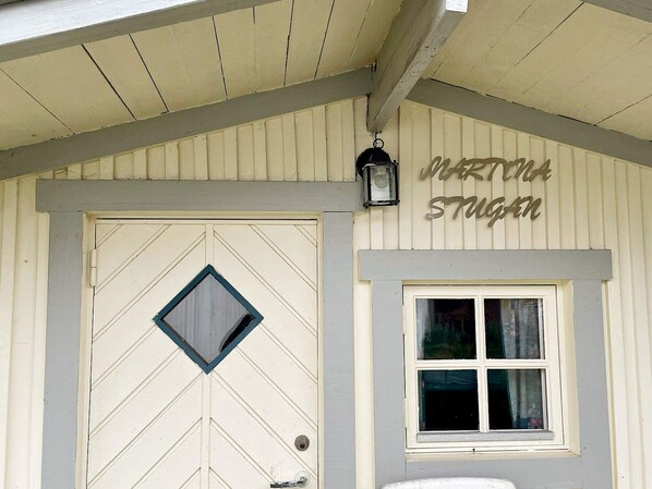 A building with a chevron-patterned door, a small window, and a sign above the door that reads 'MARTIN STUGAN'.