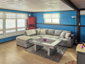 Una sala de estar con un sofá modular, una mesita de centro y un mueble de color rojo.
