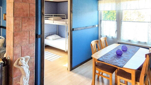 Een kamer met een stapelbed, een eettafel met stoelen, en een beeld.