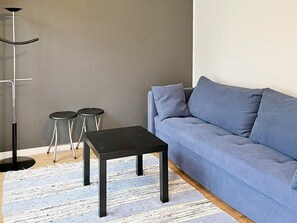A modern living room with a grey sofa, two black side tables, and a floor lamp. - 10 Person Holiday Home in Solvesborg (Sölvesborg)