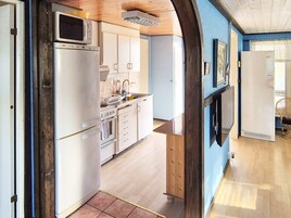 Una cucina con mobili bianchi, un forno a microonde, un frigorifero e un lavello.