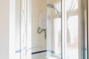 A shower with a handheld showerhead and a wall-mounted control panel, adjacent to a window with frosted glass. - Mayfield Apartments (Sunderland)