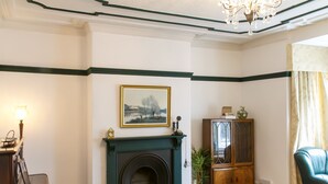 A living room with a fireplace, a framed picture on the wall, a cabinet, and a green leather sofa.