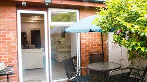 A patio area with a glass door leading to a room, a round table with chairs, and a blue umbrella.