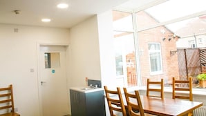 A dining area with a table and chairs, a window with a view of a brick building, and a door with a small window.