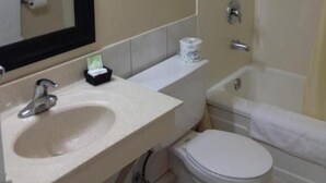 A bathroom with a sink, mirror, toilet, and bathtub. - Milestone Motel (Collingwood)