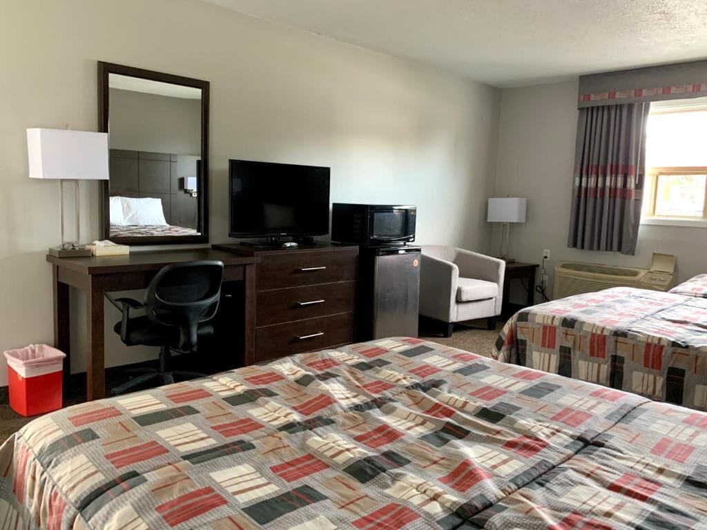 A hotel room with a bed, a desk with a computer, a television, and a chair.