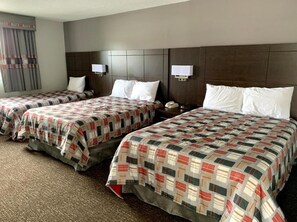 A hotel room with three beds, each with a patterned bedspread, a headboard, bedside lamps, and a telephone on the nightstand. - Milestone Motel (Collingwood)