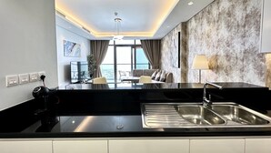 A modern kitchen with a black countertop, stainless steel sink, and a dining area with a sofa and chairs. - LuxBnB Paramount Midtown SeaView (Dubai)