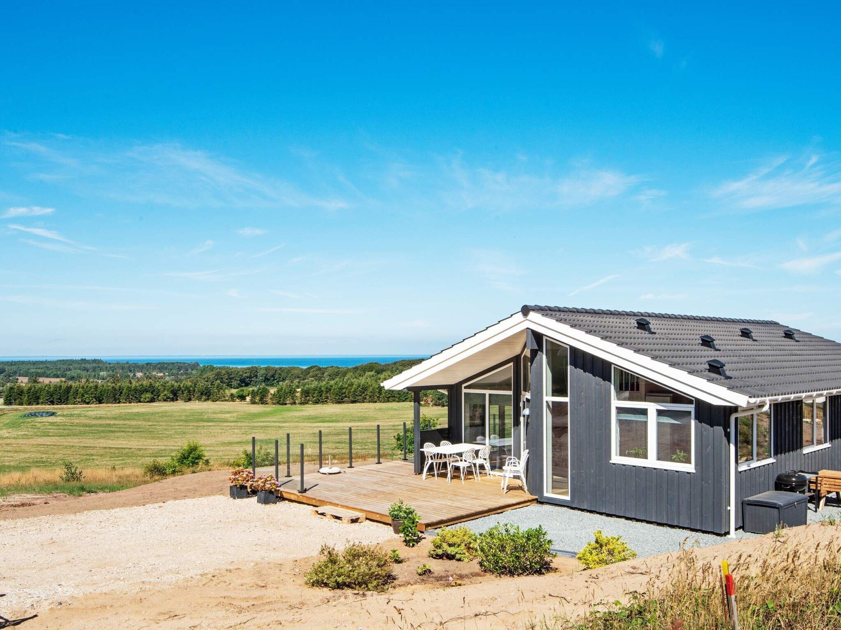A modern house with a deck, large windows, and a view of the countryside.