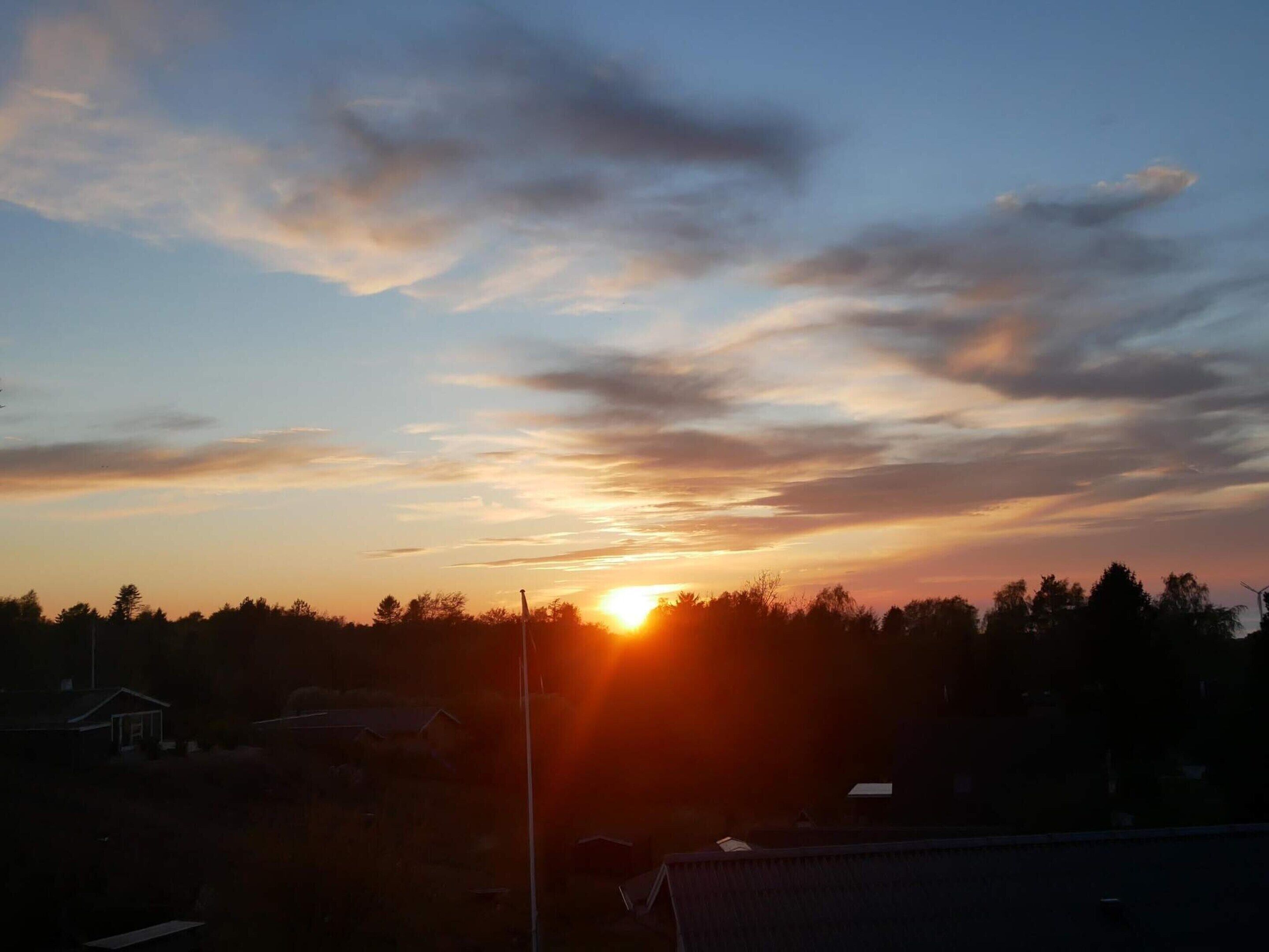 A sunset over a residential area with houses and a streetlight.