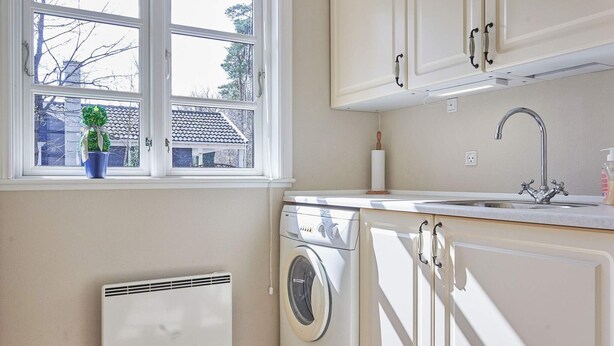 A laundry room with a washing machine, a dryer, a window with a view of a house, and a sink with a faucet. - 4 Person Holiday Home in Ronne-by Traum (Ronne)