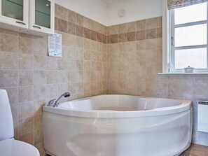 A bathroom with a freestanding bathtub, a toilet, and a window. - 4 Star Holiday Home in Ronne (Ronne)