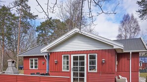 A red wooden cabin with a white door, windows, and a chimney. - 4 Person Holiday Home in Ronne-by Traum (Ronne)