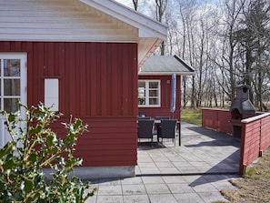A red building with a patio area, outdoor seating, and a chimney. - 4 Star Holiday Home in Ronne (Ronne)