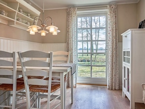 A dining area with a table and chairs, a window with curtains, and a cabinet.