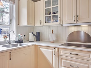 A kitchen with white cabinetry, a sink, a kettle, and a toaster.