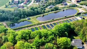 A residential area with multiple houses, a large pond, and a parking lot. - 5 Person Holiday Home in Hovborg (Hovborg)