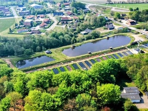 A residential area with multiple houses, a large pond, and a parking lot. - 5 Person Holiday Home in Hovborg (Hovborg)