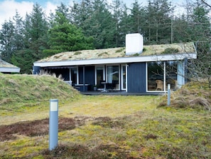 A modern house with a flat roof, large windows, and a covered outdoor seating area.
