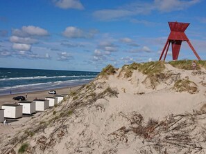 A beach with a red structure, white buildings, and the ocean.