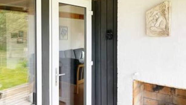 A room with a glass door, a fireplace, and a wall-mounted artwork.
