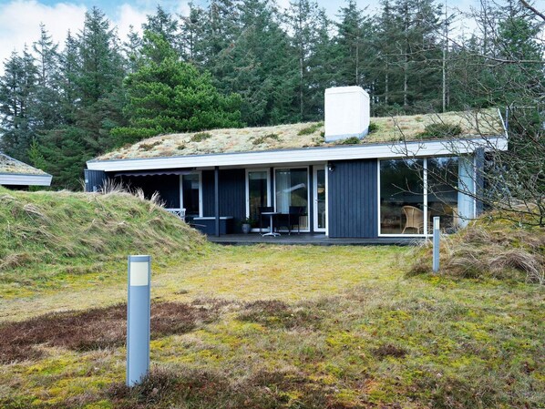A modern house with a flat roof, large windows, and a covered outdoor area.