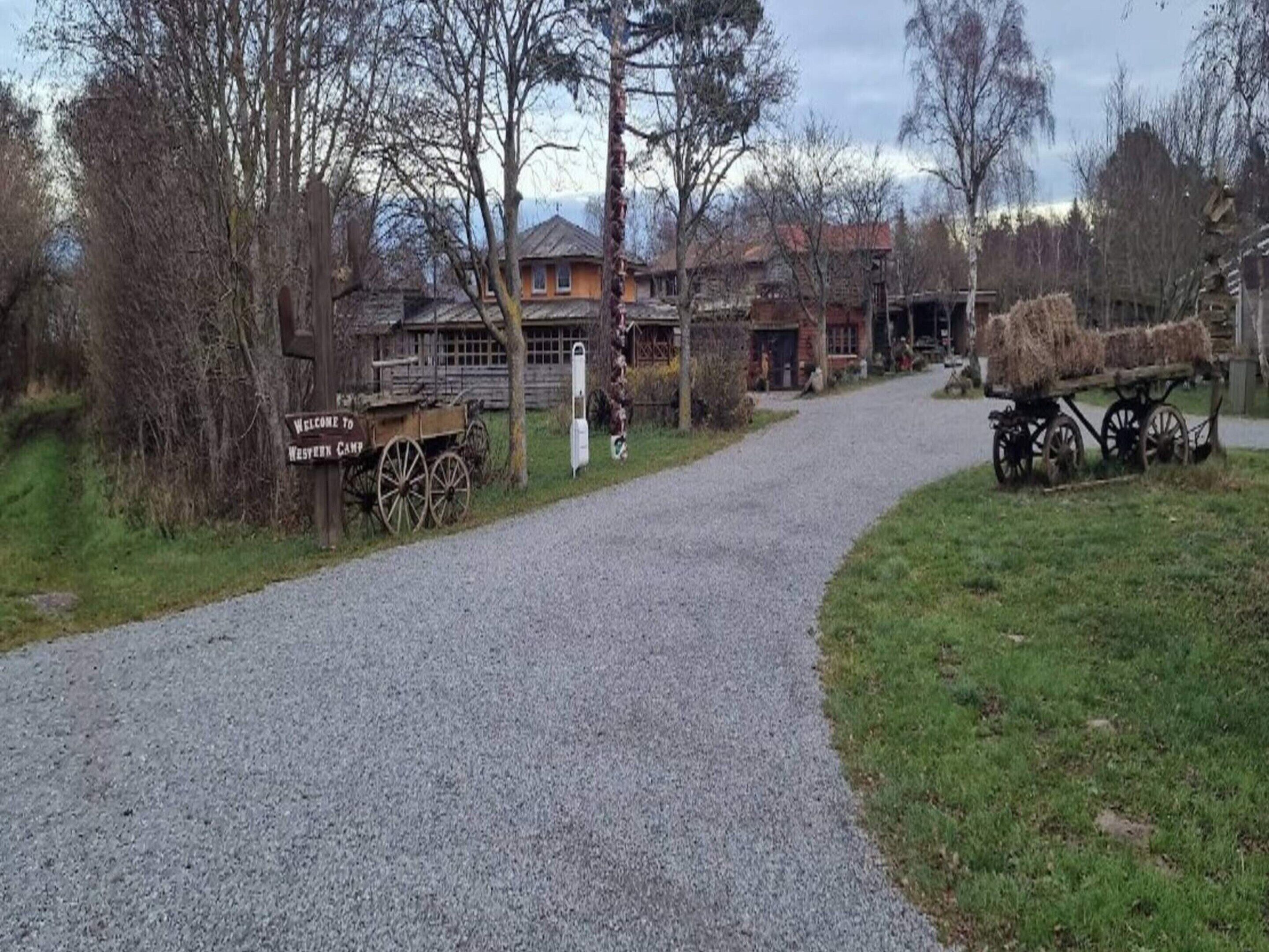 A gravel path leading to a rustic building with a 'Welcome to Wesyarn Camp' sign.