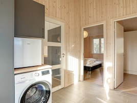 A compact room with a washing machine, a bed, and a window.