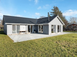A modern two-story house with a covered patio, a barbecue area, and a large sliding glass door entrance.