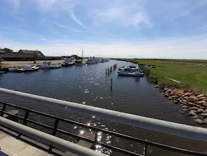 A canal with boats docked on the left, a grassy bank on the right, and a bridge in the foreground.