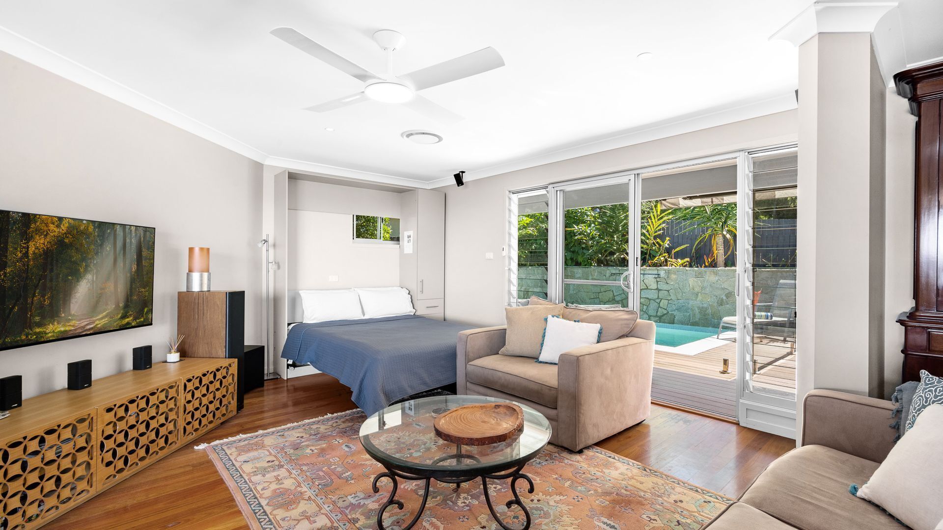 A modern living room with a bed, a sofa, a coffee table, and a TV.