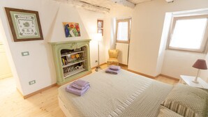 Une chambre à coucher avec un lit, une cheminée verte, une fenêtre et une porte.