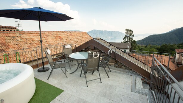 Une terrasse sur le toit avec un jacuzzi, des sièges extérieurs et une vue sur les montagnes.