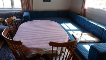 Una sala de estar acogedora con una mesa redonda, cuatro sillas de madera, un sofá azul y una alfombra estampada.