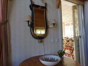 A room with a wooden-framed mirror, two wall-mounted lamps, a white bowl with a flower, and a small potted plant on a wooden table. - 5 Person Holiday Home in Mullhyttan (Mullhyttan)