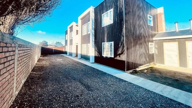 A modern building with a dark facade and multiple windows. - Alto Balmaceda Apartamentos (Natales)