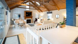 A spacious living area with a fireplace, a dining table, and a cozy seating arrangement. - Updated cottages steps from Lake Michigan beach (West Olive)