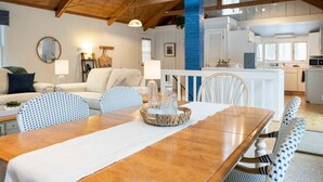 A spacious dining area with a wooden table, white chairs, and a blue accent wall. - Updated cottages steps from Lake Michigan beach (West Olive)