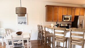 A modern kitchen with wooden cabinets, a microwave, and a refrigerator. - Second Row Condo with Ocean Views, Pool, and Hot tub (Oak Island)