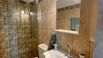 A bathroom with a toilet, sink, and shower.