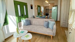 A modern living room with a sofa, two small tables, and a kitchen in the background. - Laurel LK Houses in Kritinia Rhodes (Rhodes)