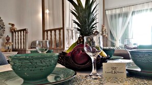 A dining table with a pineapple, a glass of water, and a glass of wine, along with a sign for 'Laurel LK Houses'. - Laurel LK Houses in Kritinia Rhodes (Rhodes)